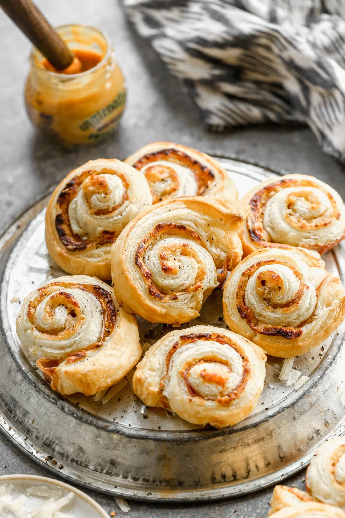 Puff Pastry Pinwheels made with store-bought puff pastry sheets, sweet and hot mustard, nutty parmigiano reggiano and  salty paper-thin slices of prosciutto. Sure to be the hit of your party!