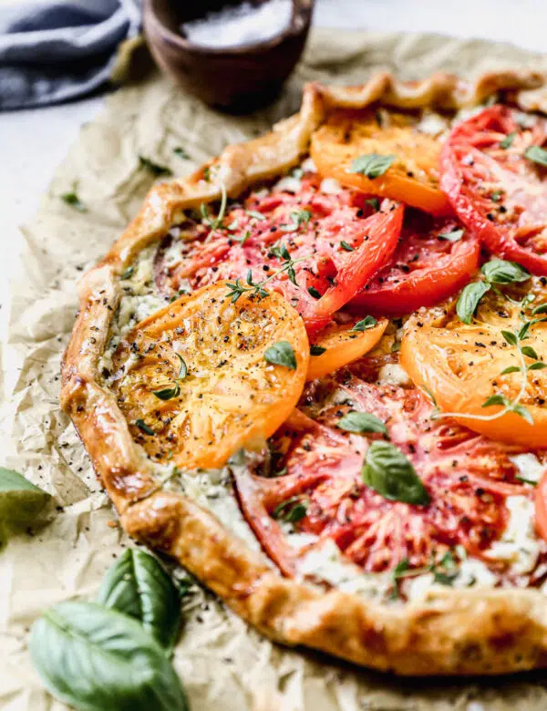 With a hidden layer of basil and gruyere-laced ricotta smothered on top of a store-bought pie crust and topped with juicy jewel-toned tomatoes, our Tomato Galette Recipe is just what you need to round out your summer.