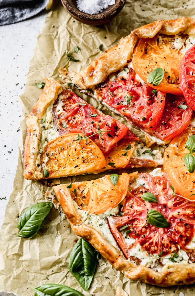 With a hidden layer of basil and gruyere-laced ricotta smothered on top of a store-bought pie crust and topped with juicy jewel-toned tomatoes, our Tomato Galette Recipe is just what you need to round out your summer.
