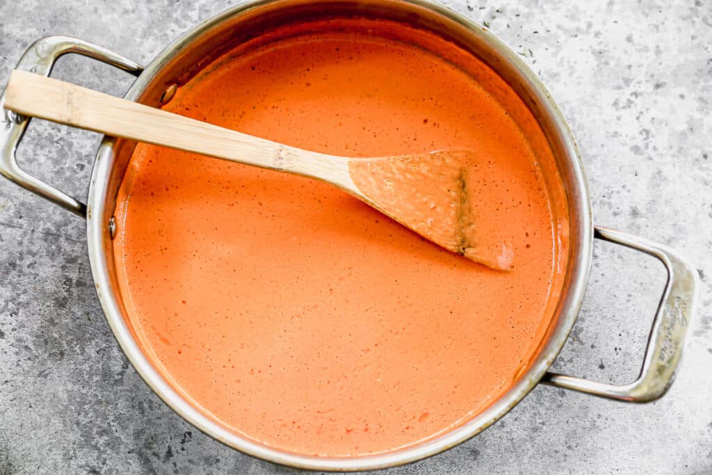 Roasted red pepper and goat cheese sauce simmering in a saucepan. 