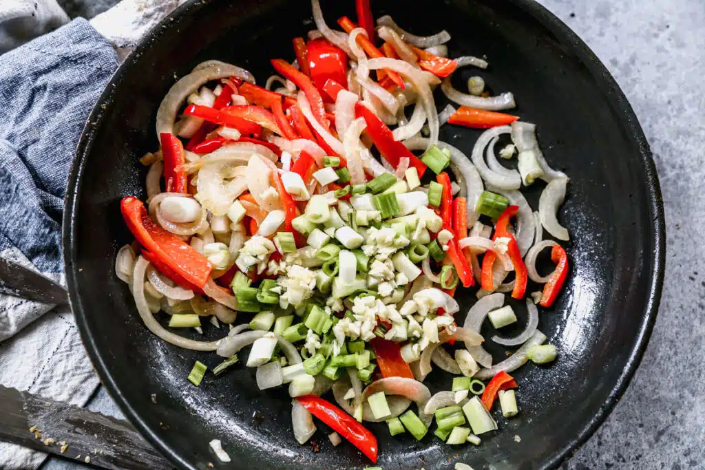 Red bell peppers, onion, green onion and garlic in a non-stick skillet