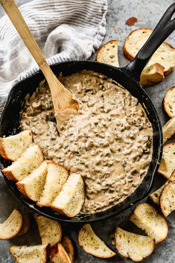 This Philly Cheesesteak Dip is SINFULLY delicious. This easy dip is packed with crispy steak, tangy provolone cheese, mozzarella, and gooey white American cheese. It’s studded with green peppers, mushrooms, and a creamy sauce, you can’t resist.