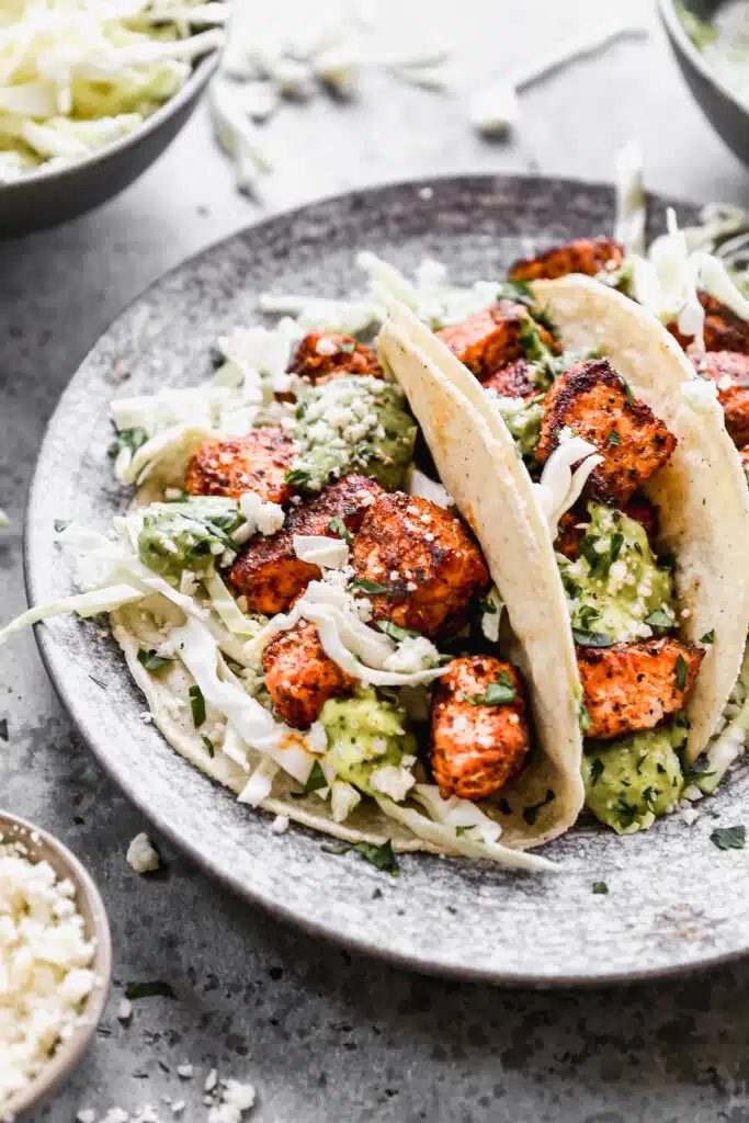 Stuffed with buttery blackened salmon bites and shredded cabbage then drizzled with a luscious Jalapeño cilantro Crema and crumbled Cotija cheese, our salmon tacos are sure to hit the seafood spot.