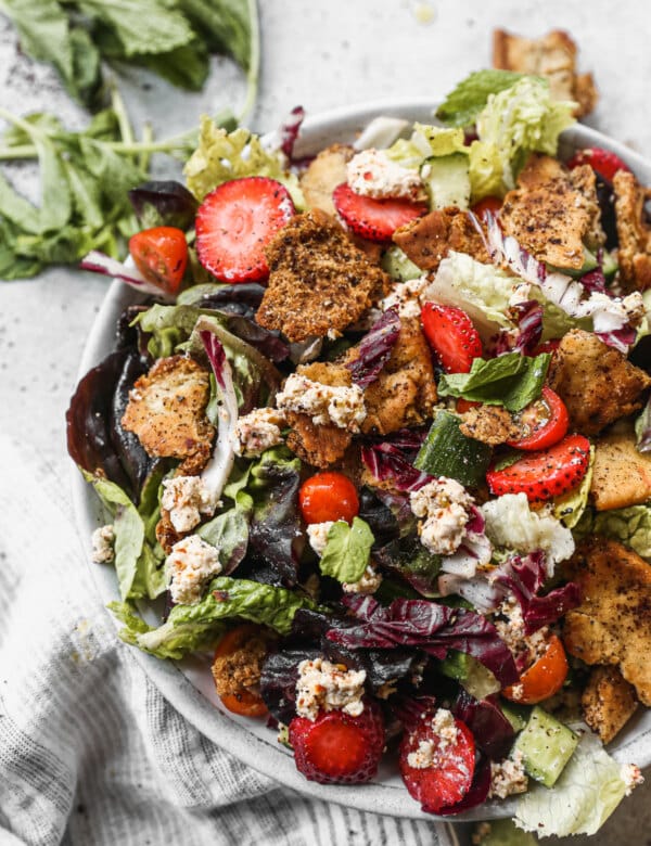 A trio of crisp lettuces, fresh veggies, sweet strawberries, tangy goat cheese and crunchy sumac-infused naan chips are the makings of our version of a Fattoush Salad Recipe. This Mediterranean-inspired salad is a bright summery salad you’ll want to eat all season long.