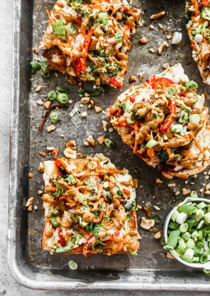 Crispy French bread doused in BBQ sauce, crisp veggies, gooey mozzarella and homemade peanut sauce are the makings of our weeknight worthy Thai Chicken Pizzas.