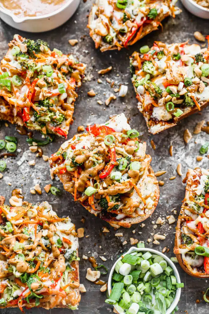 Crispy French bread doused in BBQ sauce, crisp veggies, gooey mozzarella and homemade peanut sauce are the makings of our weeknight worthy Thai Chicken Pizzas.