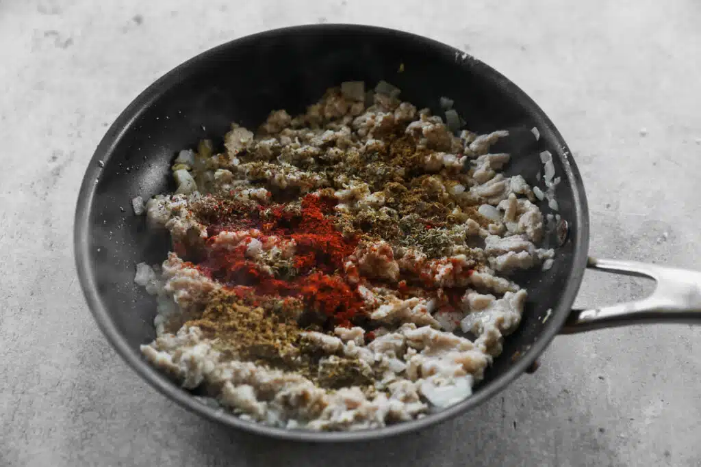 Ground chicken cooking with cumin, paprika and chili powder.