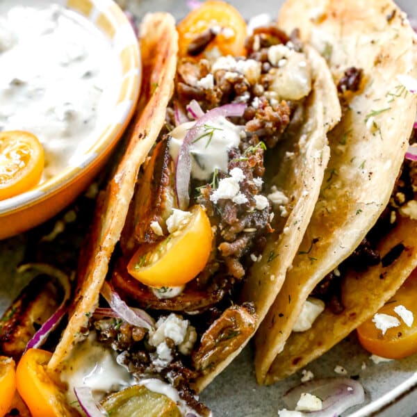 Our lamb tacos are stuffed with gyro-flavored lamb, tangy feta cheese and crisped to perfection in a hot cast-iron skillet. After the tortilla becomes ultra crispy and the feta melts into a tangy oblivion, we open them up and stuff each taco with store-bought tzatziki (another shortcut), juicy cherry tomatoes, paper-thin red onions, and plenty of fresh dill.