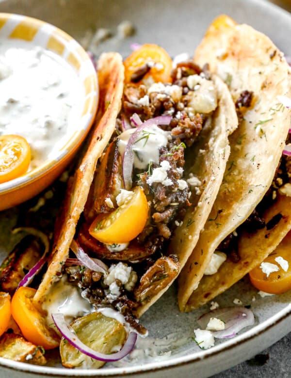 Our lamb tacos are stuffed with gyro-flavored lamb, tangy feta cheese and crisped to perfection in a hot cast-iron skillet. After the tortilla becomes ultra crispy and the feta melts into a tangy oblivion, we open them up and stuff each taco with store-bought tzatziki (another shortcut), juicy cherry tomatoes, paper-thin red onions, and plenty of fresh dill.
